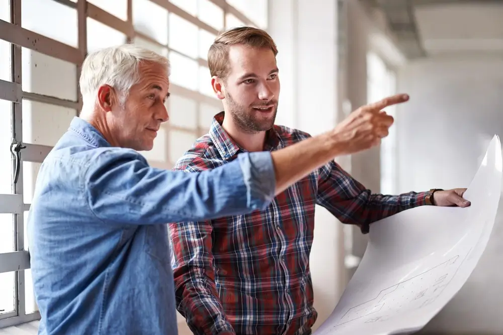 Two men reviewing a project plan on site