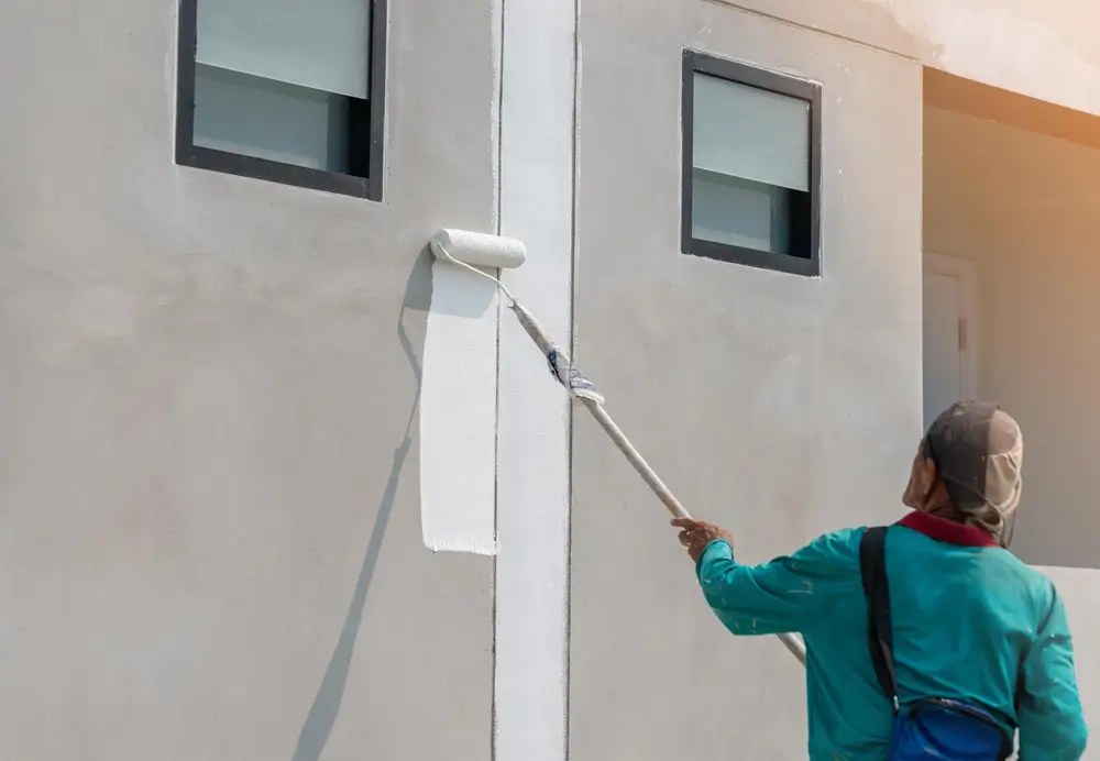 Professional painter rolling paint onto an exterior wall