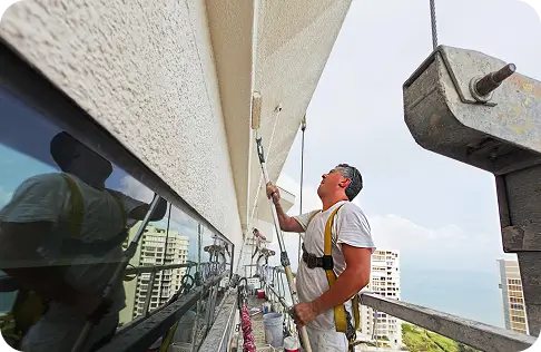 Painter working on an exterior wall of a coastal property