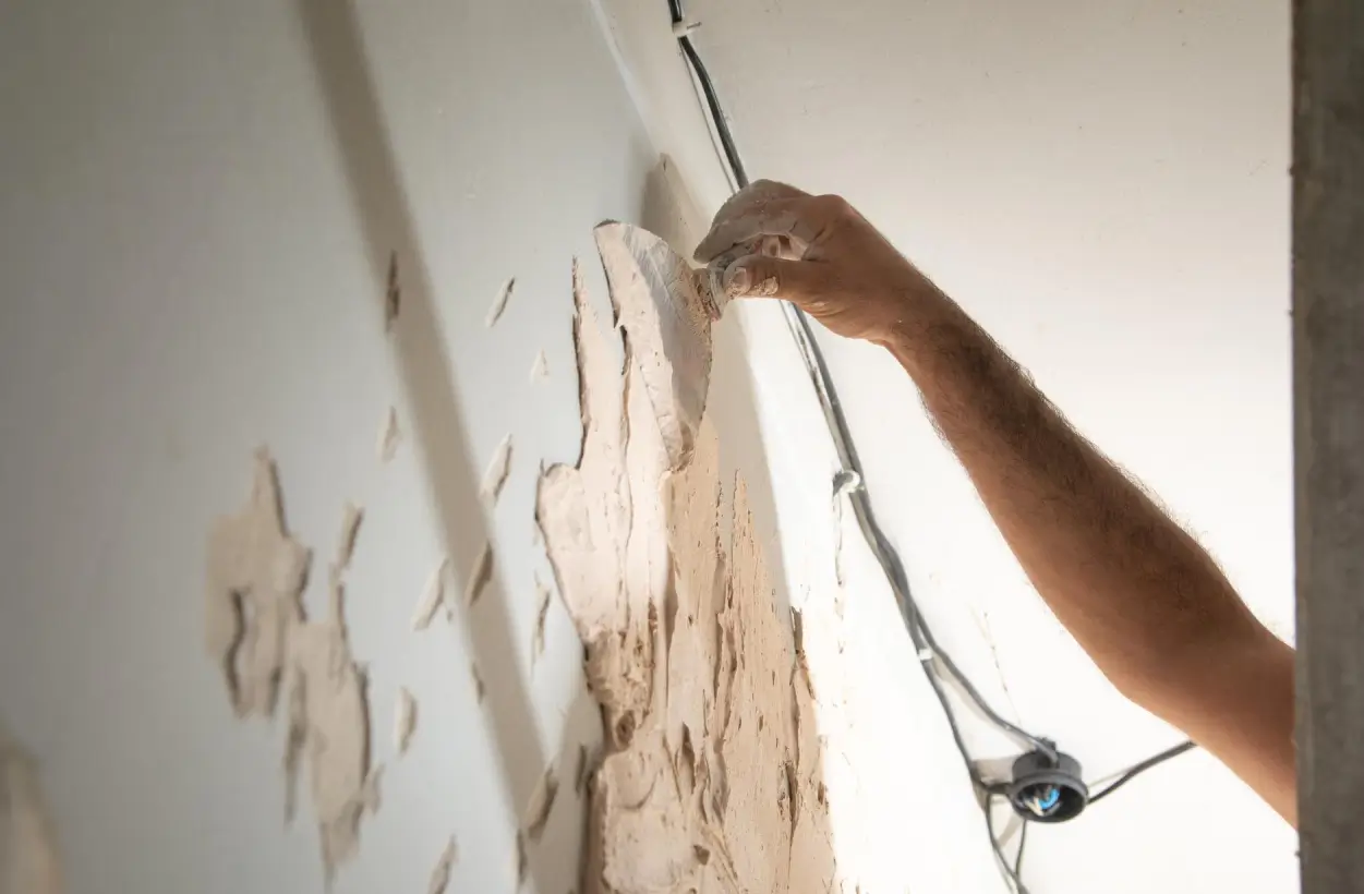 Hand smoothing a repaired patch on a wall before repainting