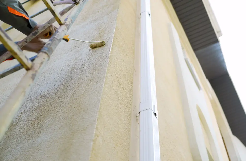 Roller loading paint at the edge of a building exterior