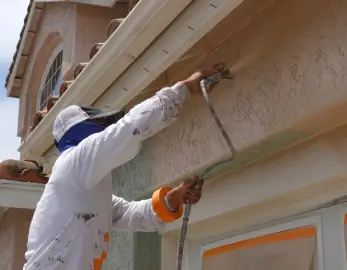 Painter in coveralls detailing exterior trim